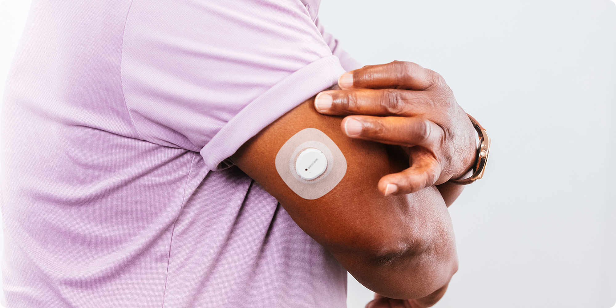 Man showcasing glucose sensor on his arm
